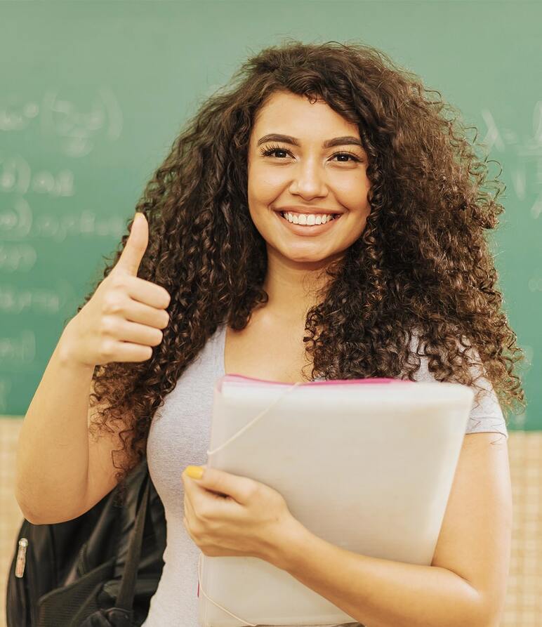 Happy smiling new teacher at the front of a classroom.